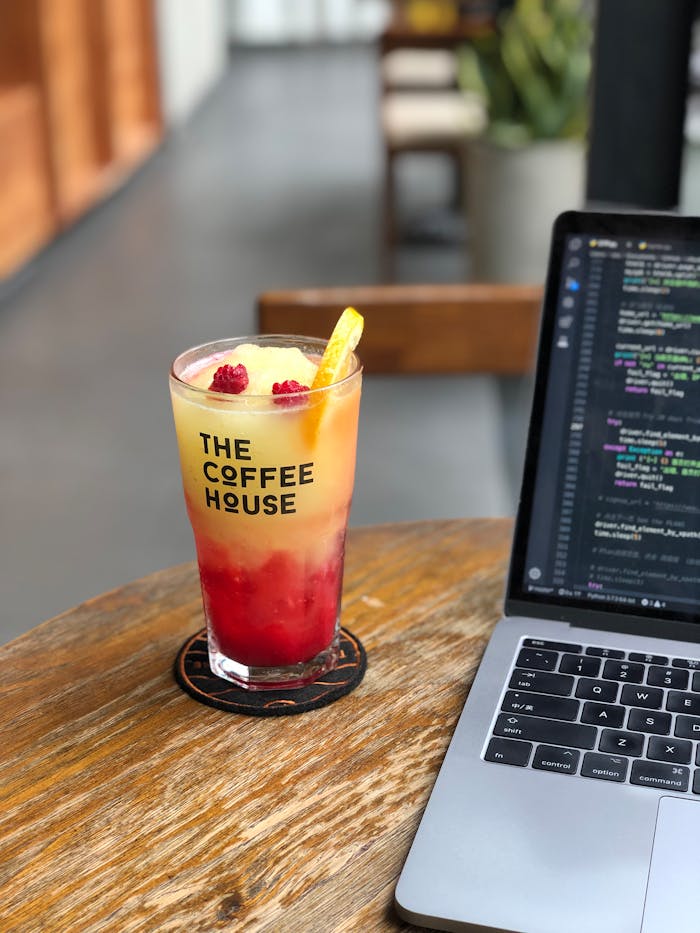Chilled raspberry lemonade and coding on a laptop at a modern coffee house.